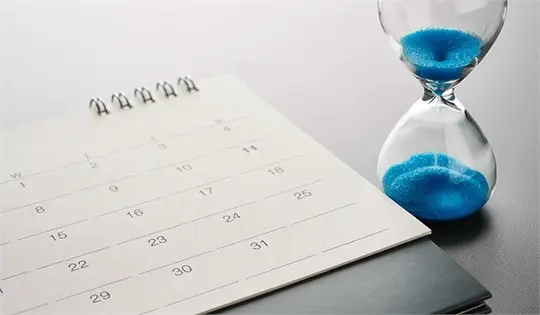 a calendar and hourglass with blue sand