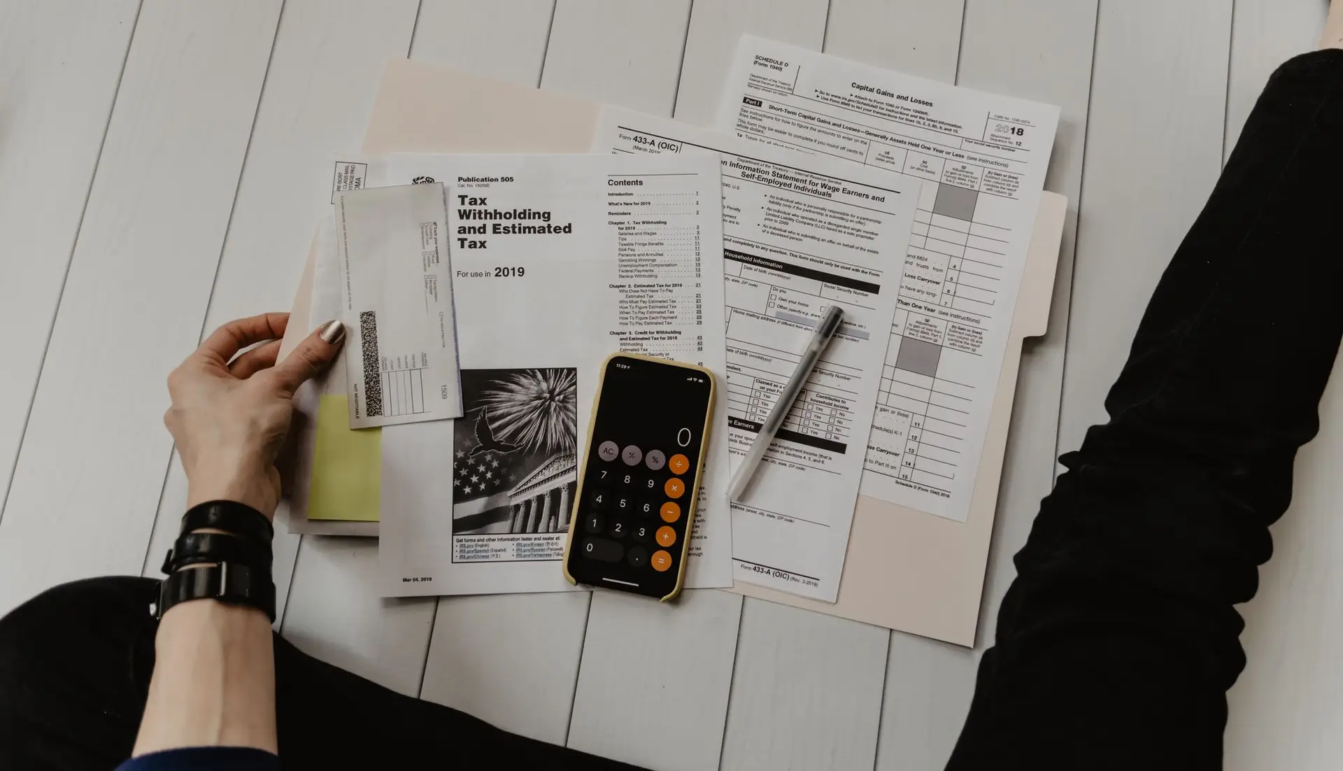 a person holding a pen and a tax form