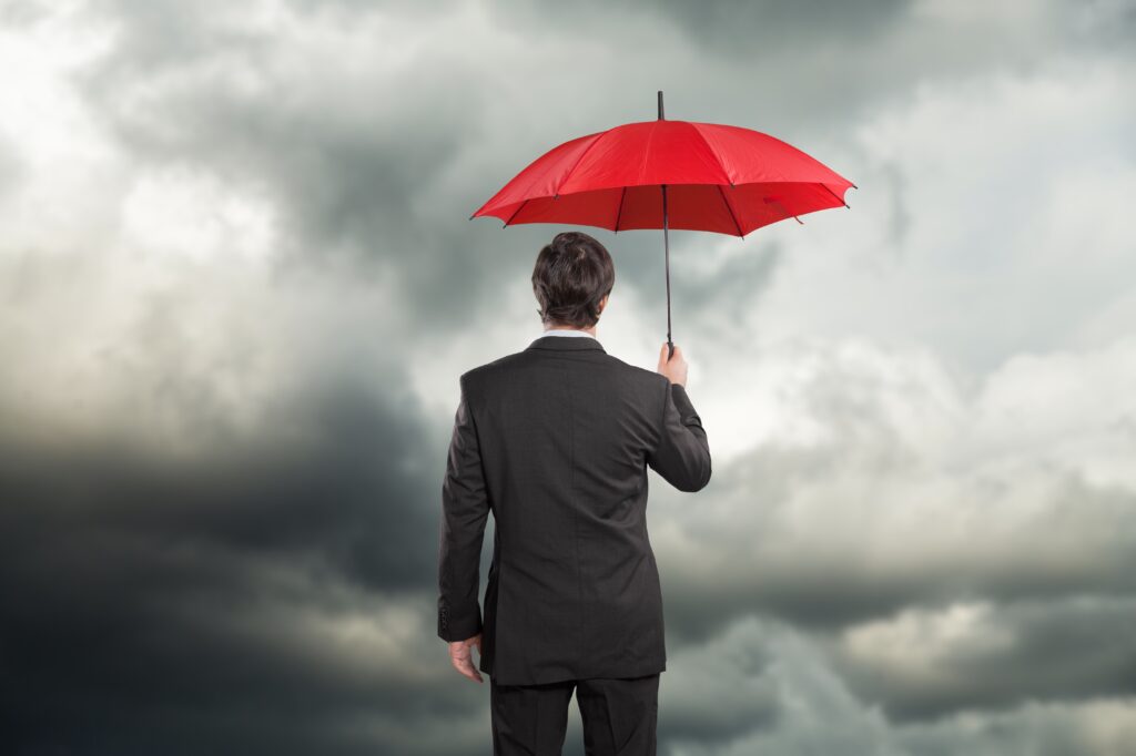 businessman with red umbrella gray sky background